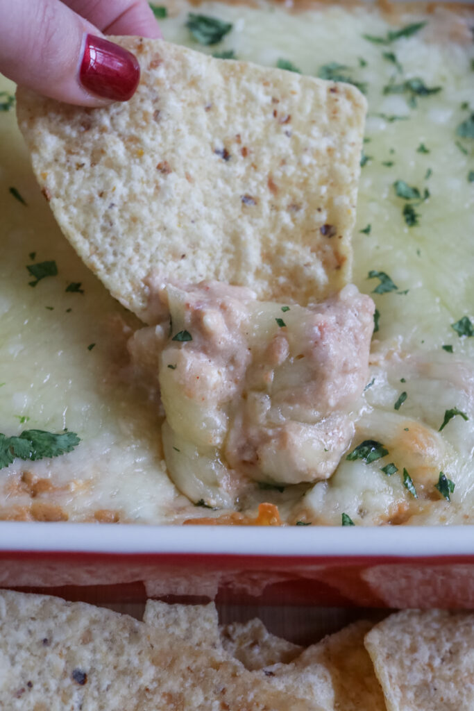 a tortilla chip being dipped in refried bean dip