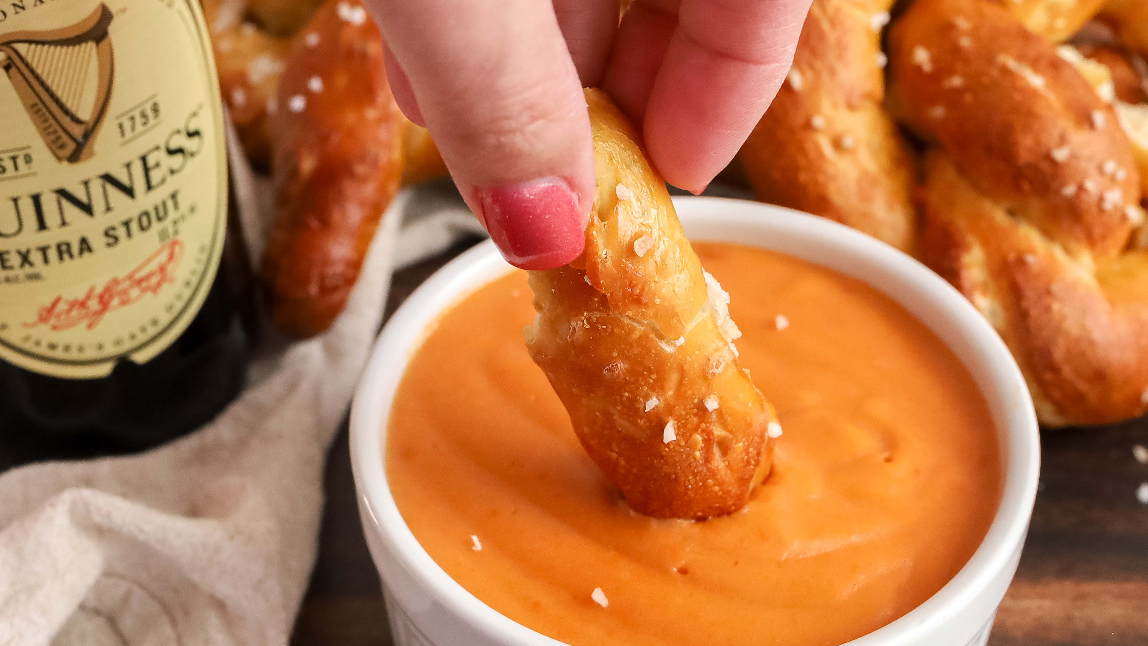 Pretzel being dipped in beer cheese