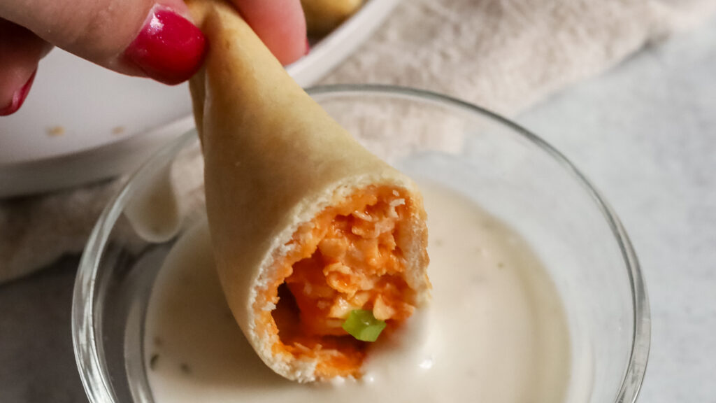 Empanada being dipped in dressing