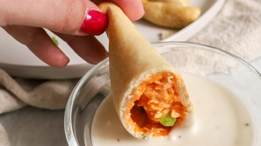 buffalo chicken empanada being dipped