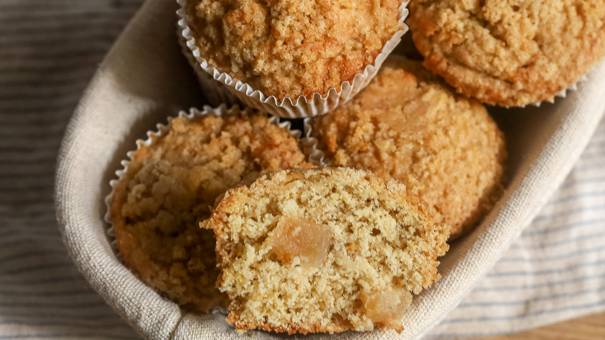 a cut up apple pie muffin in a pile of muffins